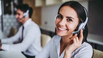 Smiling customer support agent wearing a headset at a desk