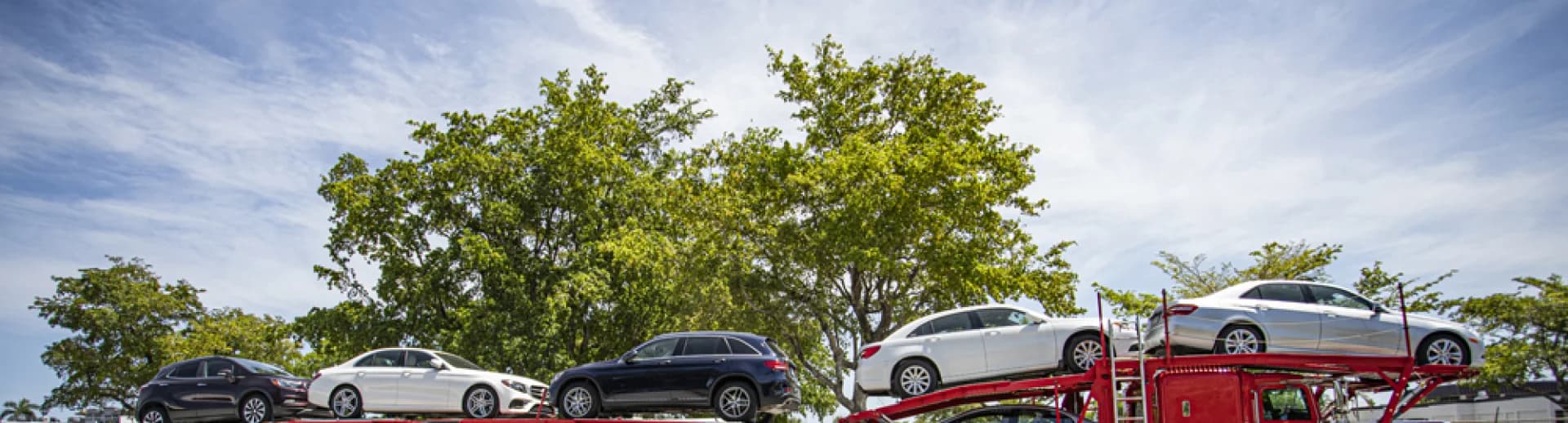 Professional car carrier truck transporting multiple vehicles on highway at sunset