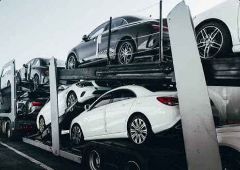 car hauler truck loaded with multiple vehicles showing auto transport on highway