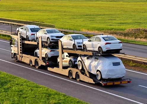 multi level car hauler driving on highway transporting several vehicles across long distance