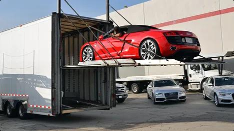 Enclosed auto transport Red convertible loaded on a hydraulic lift gate into an enclosed car trailer