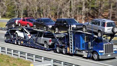 Open carrier auto transport Blue semi car hauler transporting SUVs and sedans on a double deck open trailer on the highway