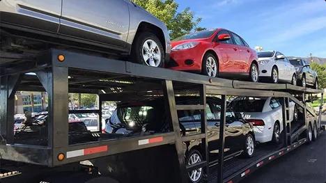 Open Carrier Auto Transport Double deck open car carrier loaded with sedans in a parking lot under blue sky