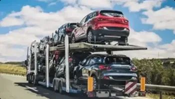 multiple vehicles on a red auto transport trailer on the highway