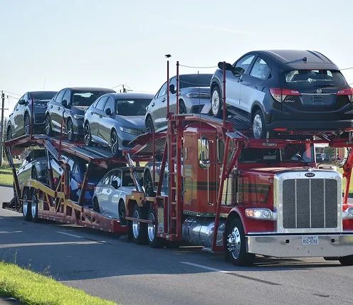 Open carrier loaded with sedan cars open car carrier loaded with multiple sedans driving on a roadway