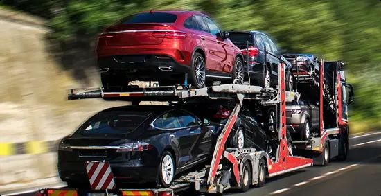 Open carrier transporting cars on highway open car carrier transporting sedans and SUVs on a highway curve