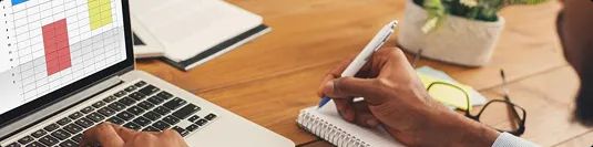 Transport cost analysis and planning person analyzing transport cost data on laptop and writing notes for planning