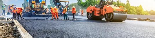 Road construction and vehicle transport routes road construction workers paving fresh asphalt to improve vehicle transport routes