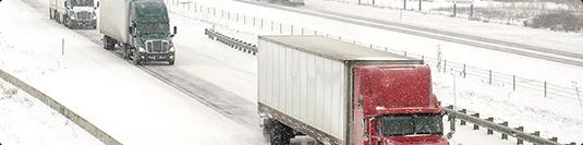 Weather conditions trucks driving on a snowy road illustrating weather delays