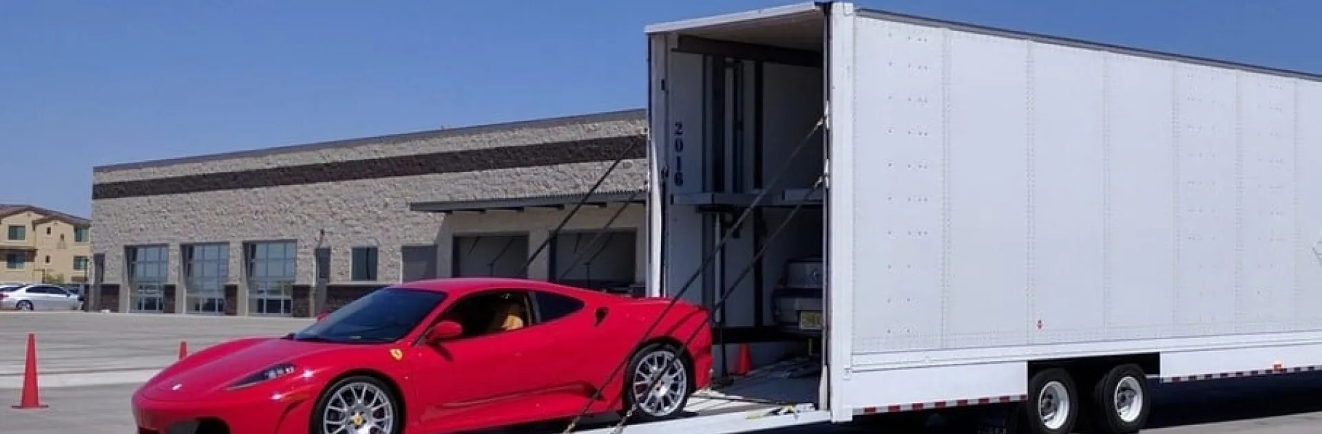 Enclosed auto transport hero red sports car being loaded into enclosed trailer for secure transport