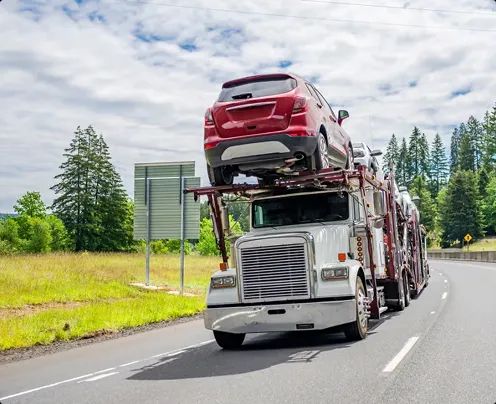 Open carrier transporting SUV on highway open car carrier transporting a red SUV on a highway