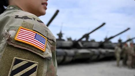 Military car shipping support for PCS moves us flag patch on soldier uniform with tanks in background symbolizing military car shipping and pcs moves