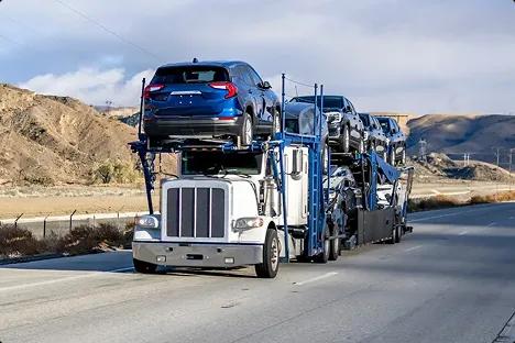 Enclosed car carrier on interstate blue and white car carrier truck transporting vehicles on open highway