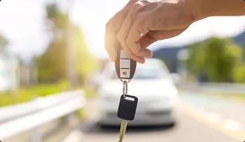 Safe to your home or dorm hand holding car keys with blurred car in background for safe delivery