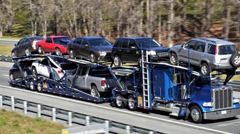 Open carrier auto transport Blue semi car hauler transporting SUVs and sedans on a double deck open trailer on the highway