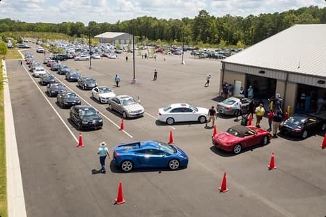 Auto auction inspection lane Long line of cars waiting at an auto auction inspection lane with orange cones and staff