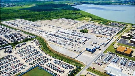 Auto auction vehicle lot Aerial view of a large auto auction yard with rows of parked vehicles near a lake