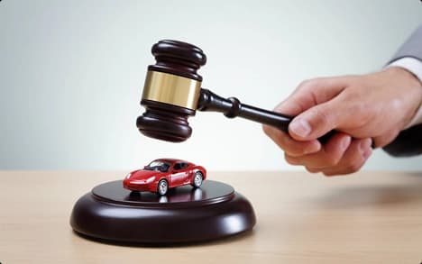 Auto Auction Car Transport Judge gavel striking near a small red car model symbolizing auto auction purchases and releases