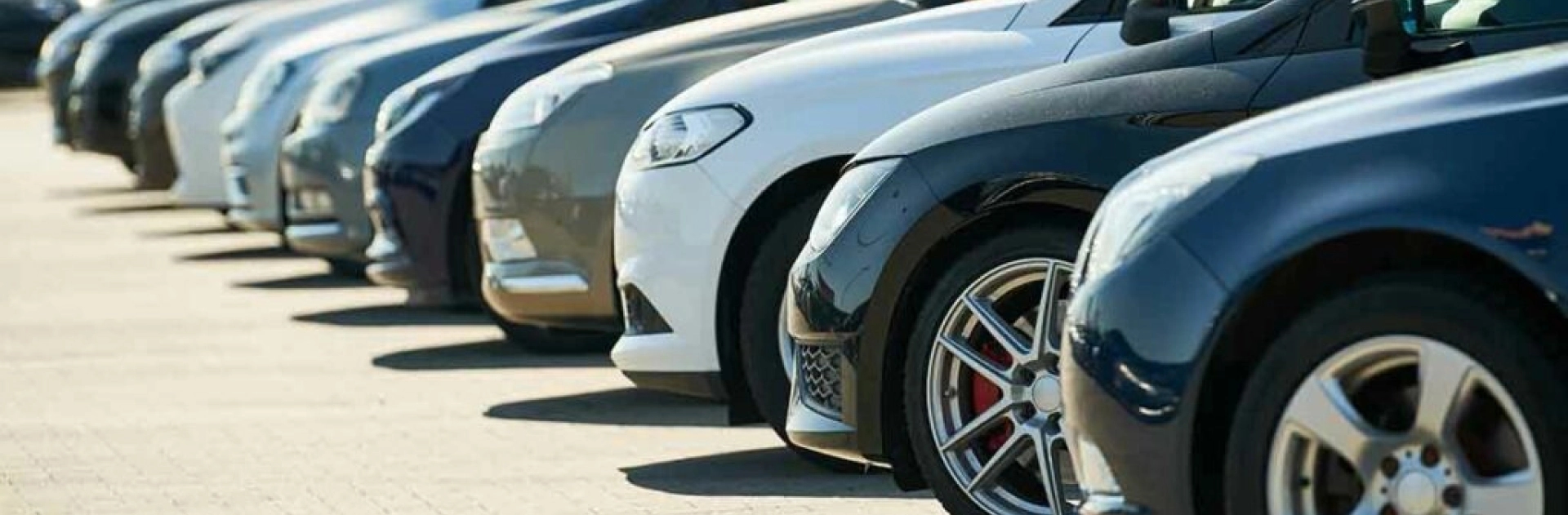 Auto dealership transport solutions Row of cars in a dealership lot, close up of wheels and fenders, auto dealership transport hero