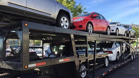 Open Carrier Auto Transport Double deck open car carrier loaded with sedans in a parking lot under blue sky