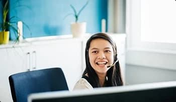smiling customer service representative wearing headset at desk