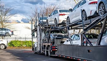 Open carrier loaded for dealer transport open car carrier loaded with sedans near trees ready for dealer transport