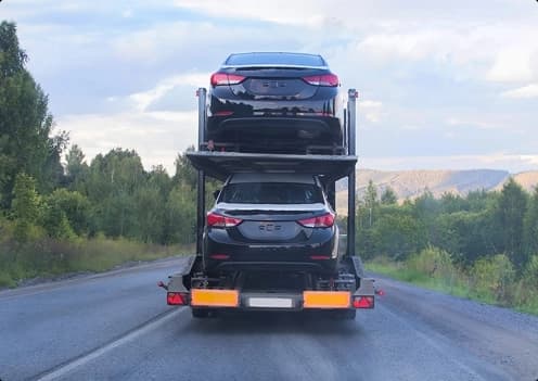 Car Carrier Trailer on Forest Highway car carrier trailer transporting vehicles on a forest highway during daytime