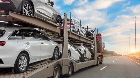 Open carrier car shipping on highway multi level open car carrier transporting vehicles on highway at sunrise showing affordable car shipping