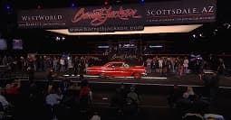 Classic car auction transport service classic car on auction stage under spotlights with audience in dark venue