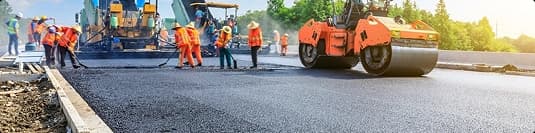 Road construction and vehicle transport routes road construction workers paving fresh asphalt to improve vehicle transport routes
