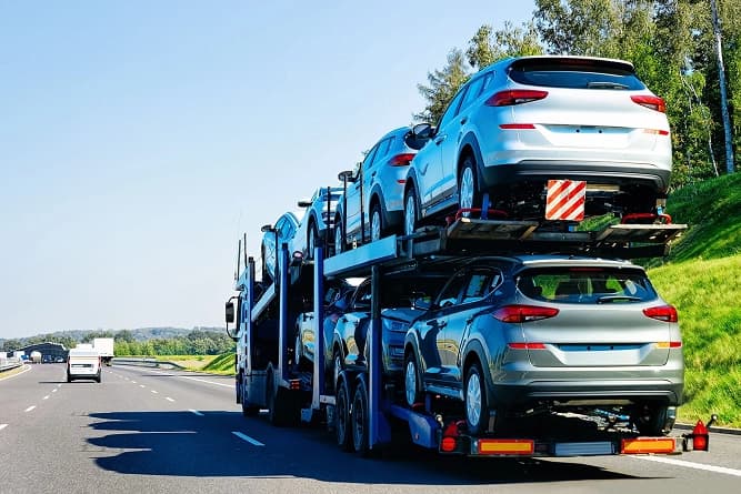 Open car transport trailer loaded with vehicles open transport trailer loaded with several cars parked outdoors