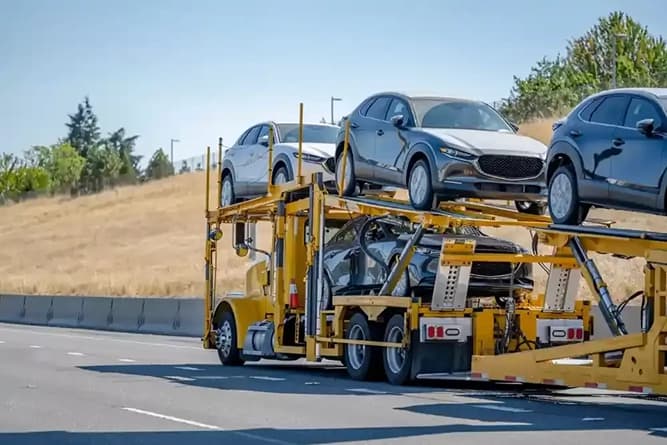 Car hauler transporting multiple vehicles on highway car hauler carrying multiple vehicles on an open trailer driving on highway