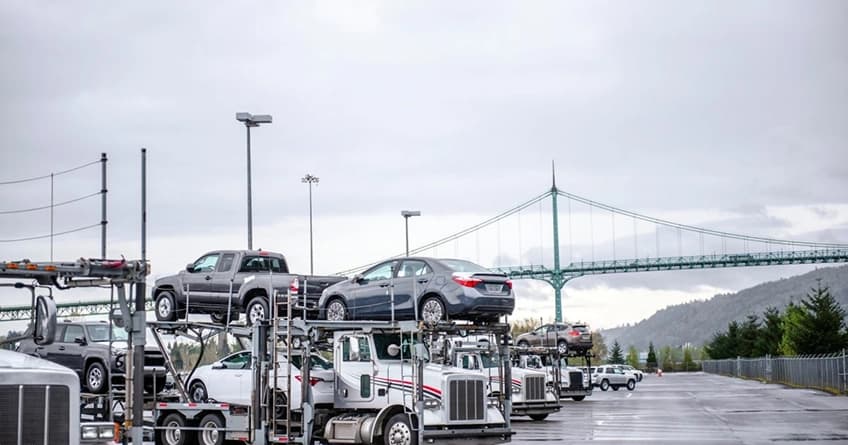 Car transport trucks parked near bridge on cloudy day car transport trucks parked near a bridge on a cloudy day