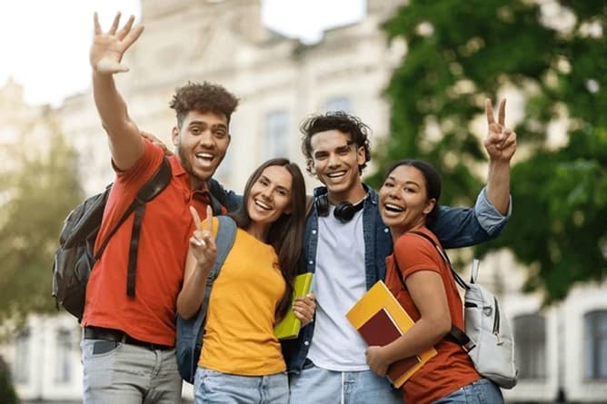 College students smiling and holding books outdoors group of college students smiling outdoors holding books and backpacks