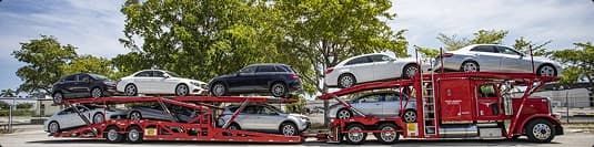 Open car hauler red truck red open car hauler loaded with multiple vehicles parked roadside