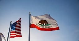 California Car Shipping California Bear Flag on a pole beside the U.S. flag under clear sky