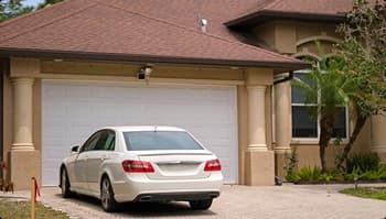 Residential Pickup And Delivery White sedan parked in a suburban driveway for residential pickup or delivery