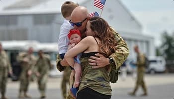 Trusted transport for pcs and deployments service member hugging family on tarmac with us flag after deployment symbolizing trusted transport