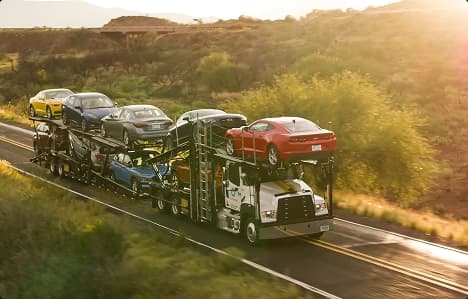 Open car hauler on desert highway open car hauler transporting multiple vehicles on desert highway at sunset