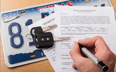 Auto insurance paperwork with Texas license plate person signing car insurance papers beside Texas license plate and keys