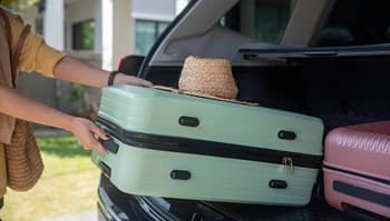Packing for seasonal move and car transports person loading suitcases into suv trunk for seasonal move and car transport