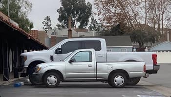 Truck size comparison small and heavy duty small pickup parked next to lifted heavy duty truck in a parking lot showing different truck sizes